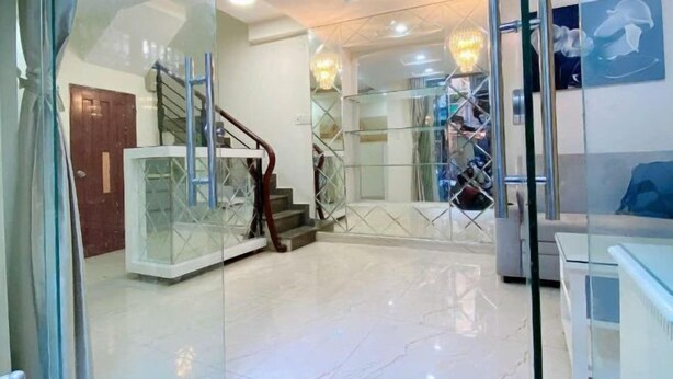 Un interior moderno con una escalera de cristal, una puerta de madera y un candelabro.