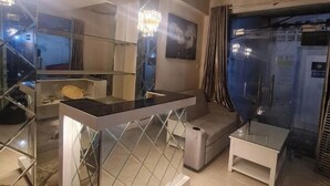 Un baño moderno con separador de vidrio, un pequeño banco blanco y una araña.