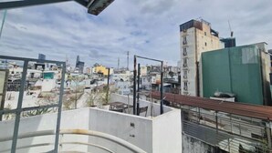 Terraza en la azotea con vistas a una zona urbana densamente poblada, que combina edificios residenciales y comerciales.