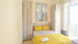 Un dormitorio con cama, un cuadro, un armario y una ventana.