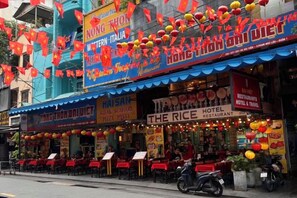 A restaurant with outdoor seating, a sign for 'The Rice Restaurant,' and a 'Hotel & Travel' sign. - The Owl Town 2 - Cosy Homestay Nearly Bui Vien Ewlaking Street (Ho Chi Minh City)