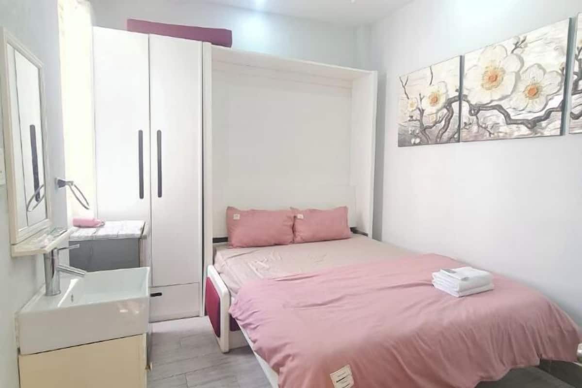 A bedroom with a bed, a wardrobe, a mirror, and a painting on the wall.