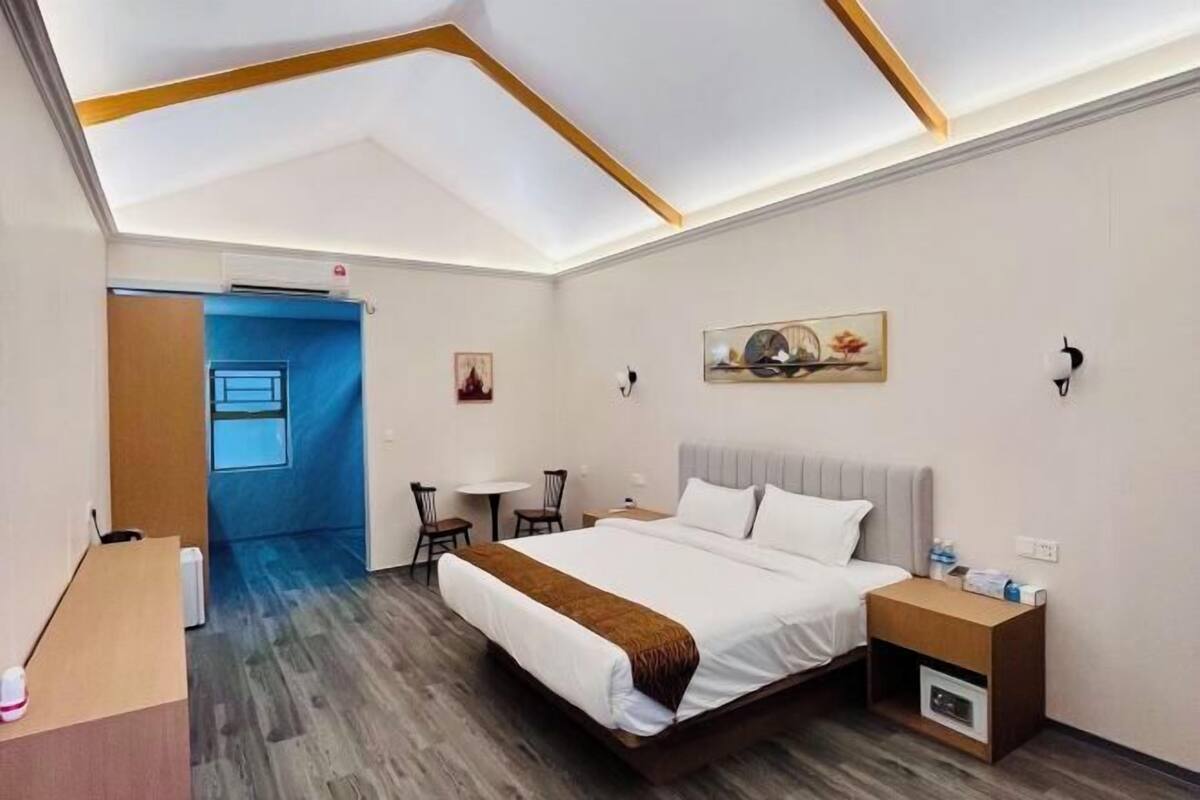 A hotel room with a bed, bedside tables, a desk, and a small table with chairs.