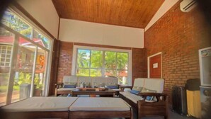 A room with a brick wall, large windows, a bed, a sofa, and a table. - MANJU SEMPORNA RESORT (Semporna)