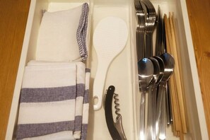 A drawer with neatly arranged kitchen utensils including a spatula, forks, spoons, and a knife. - PIER & JETTY - Shiratori 2 (Osaka)