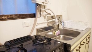 A kitchen with a gas stove, a sink, and a microwave. - PIER & JETTY - Shiratori 2 (Osaka)