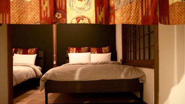 A bedroom with two beds, a window with bars, and patterned curtains. - PIER & JETTY - Shiratori 2 (Osaka)