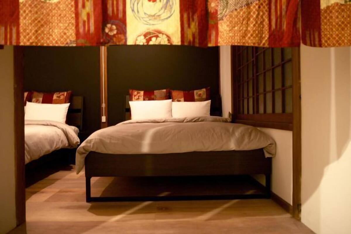 A bedroom with two beds, a window with bars, and patterned curtains.