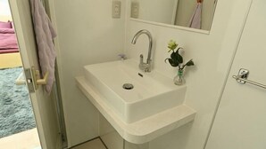 Een badkamer met een witte wastafel, een spiegel en een handdoekhouder.