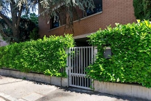 Un lotissement résidentiel fermé, avec un bâtiment en briques, un chemin en béton et une végétation luxuriante.