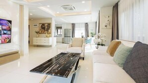 Una sala de estar moderna con una mesa de centro de mármol, un sofá y un televisor.