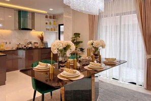 Un comedor moderno con una mesa de vidrio, sillas verdes y flores blancas.
