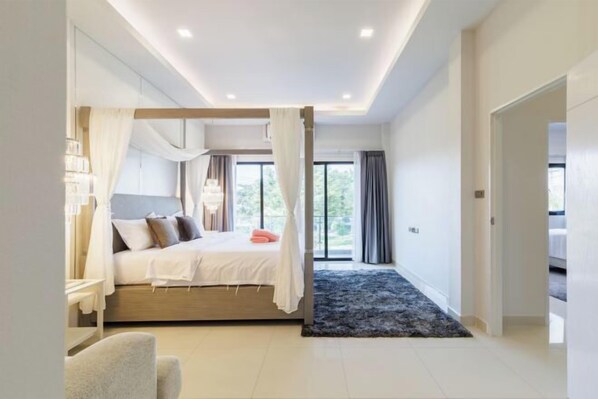 A modern bedroom with a bed, bedside table, and a view of the outdoors.
