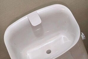 Un évier rectangulaire blanc et vide, muni d’un robinet.