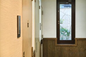 Un couloir avec une porte en bois et une petite fenêtre.