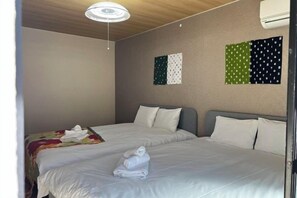 Une chambre d’hôtel avec deux lits, un luminaire au plafond et un mur décoré de motifs en forme de drapeaux.