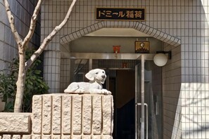 A building entrance with a stone wall, a dog statue, and a sign above the door. - Rest Collection Fushimi-Inari Kyoto (Kyoto)