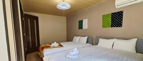 A hotel room with two beds, a wooden ceiling, and an air conditioning unit.