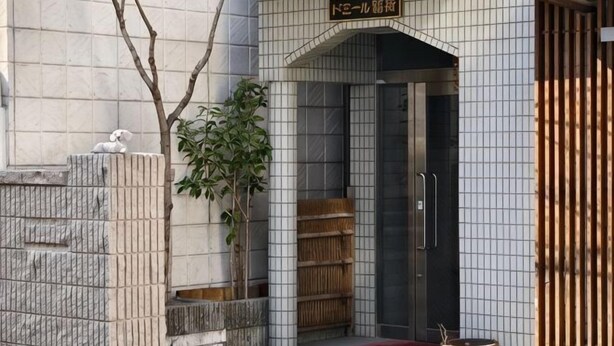 A building entrance with a tiled facade, a wooden gate, and a potted plant. - Rest Collection Fushimi-Inari Kyoto (Kyoto)