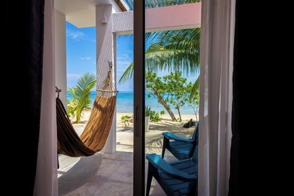 Una habitación con vista a la playa, una hamaca y un sillón.