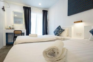 A hotel room with two beds, a desk, a chair, and a large window with curtains.