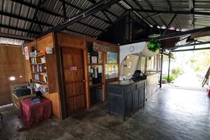 A covered outdoor area with a wooden structure, a counter, and a signboard.