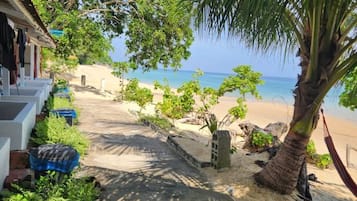 Ein Weg, der zu einem Strand mit einer Palme und einer Hängematte führt.