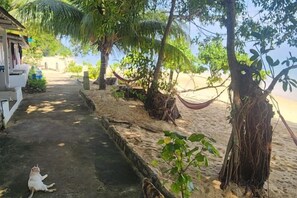 A pathway leading to a beach area with a hammock and trees. - Coral Reef Holidays (Tioman)