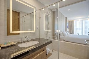 Un baño moderno con un espejo grande, un lavamanos y una ducha.
