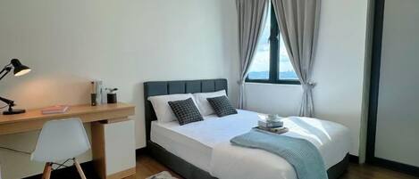 Quarto com cama, escrivaninha, cadeira e janela com cortinas.