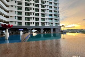 Un hotel con area piscina, un edificio grande su più piani e vista sul tramonto.