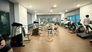 Ein Fitnessstudio mit verschiedenen Trainingsgeräten, darunter Laufbänder und Kraftgeräte, sowie einem Holzboden.