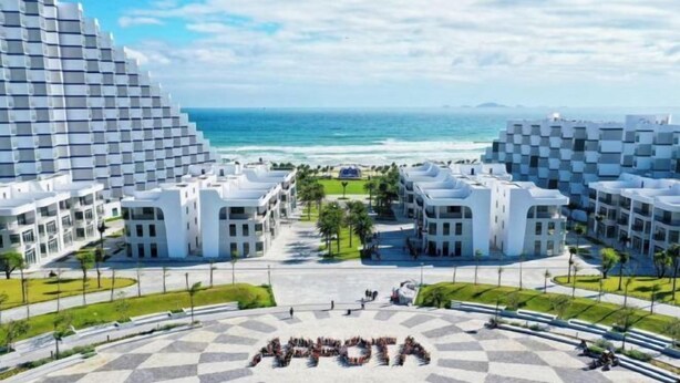 A modern hotel with a central courtyard, multiple floors, and a view of the ocean. - The KH Arena Cam ranh Nha trang Beachside (Cam Ranh)