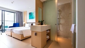 A modern hotel room with a large bed, a bathroom with a glass shower, and a view of the city. - The KH Arena Cam ranh Nha trang Beachside (Cam Ranh)