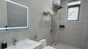 A modern bathroom with a large mirror, a white sink, a toilet, and a shower. - Niki Homestay (Hue)