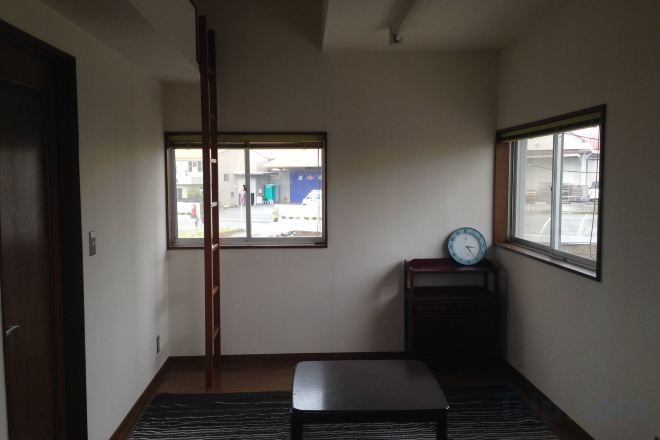 A room with a sliding door, a bench, a clock on a stand, and a window with a view of the outside.