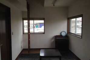 Quarto com porta deslizante, um banco, um relógio sobre pedestal e janela com vista para o exterior.