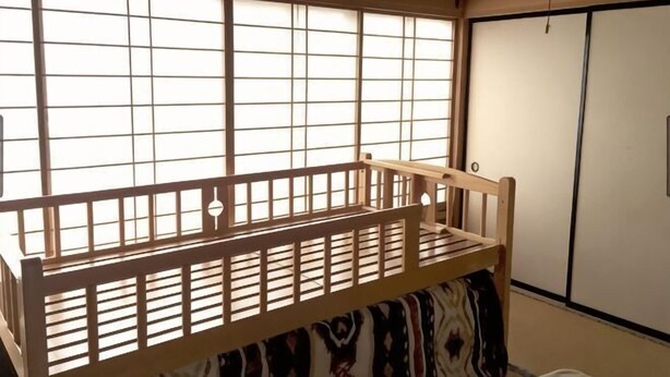 A room with a tatami mat floor, a wooden bed with a headboard, a sliding door, and a window with a grid pattern. - Mt.Fuji Homestay Leoya (Fuji)