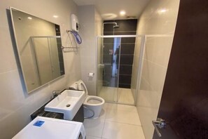 A modern bathroom with a glass shower enclosure, a white sink, and a toilet. - Seafront Country Garden Danga Bay by Lions Bay (Johor Bahru)