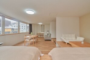 Moderni hotellihuone, jossa on suuri ikkuna, ruokailutila, sohva ja sänky.