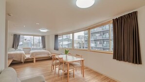 A modern apartment with a dining area, a sofa, and a large window with curtains. - The Stay Yuki (Otaru)