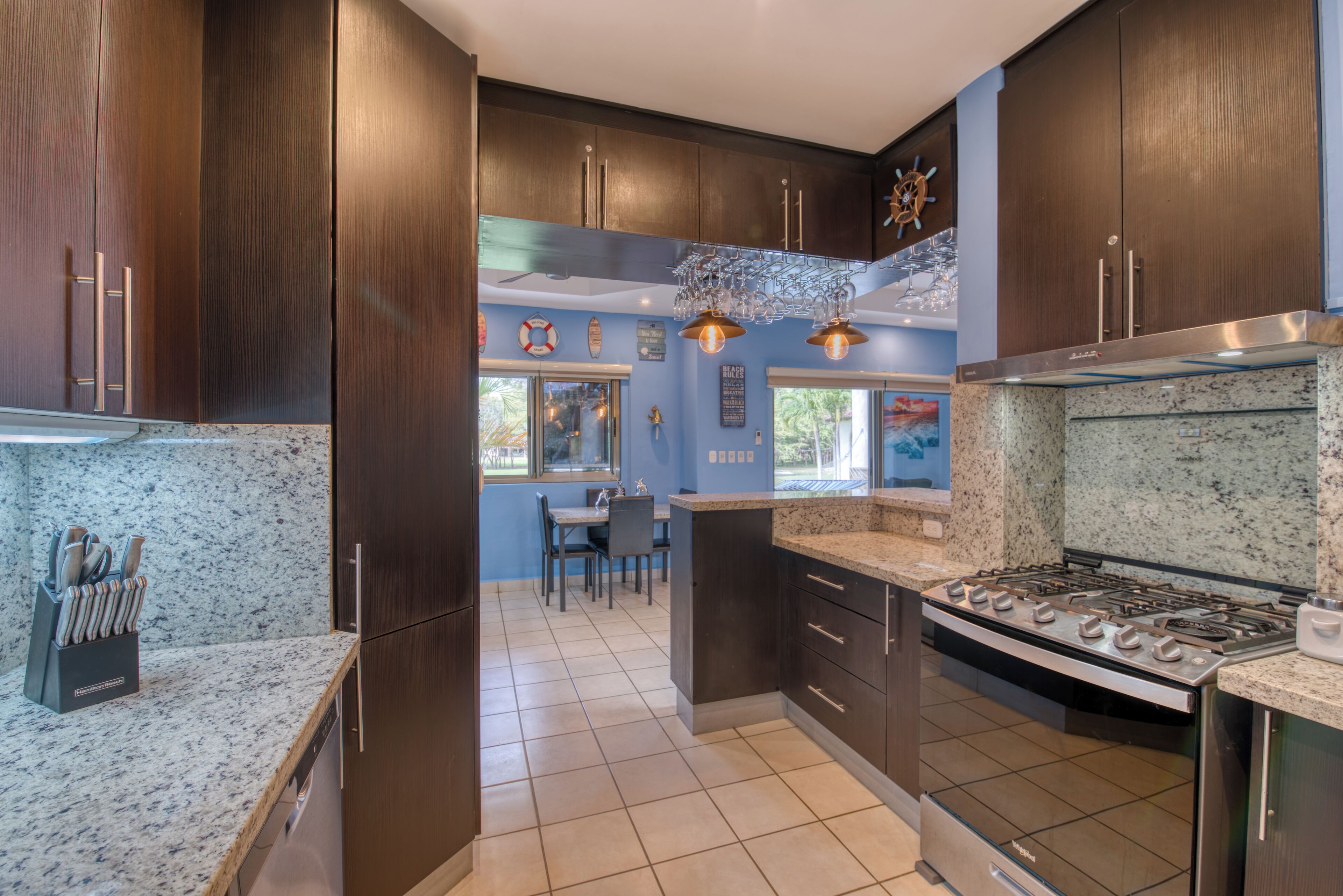 Una cocina moderna con armarios de madera oscura, encimera de granito y estufa de acero inoxidable.