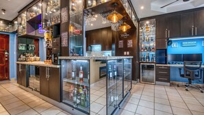 A modern kitchen with a bar area, featuring stainless steel appliances, glass cabinets, and a variety of bottles.