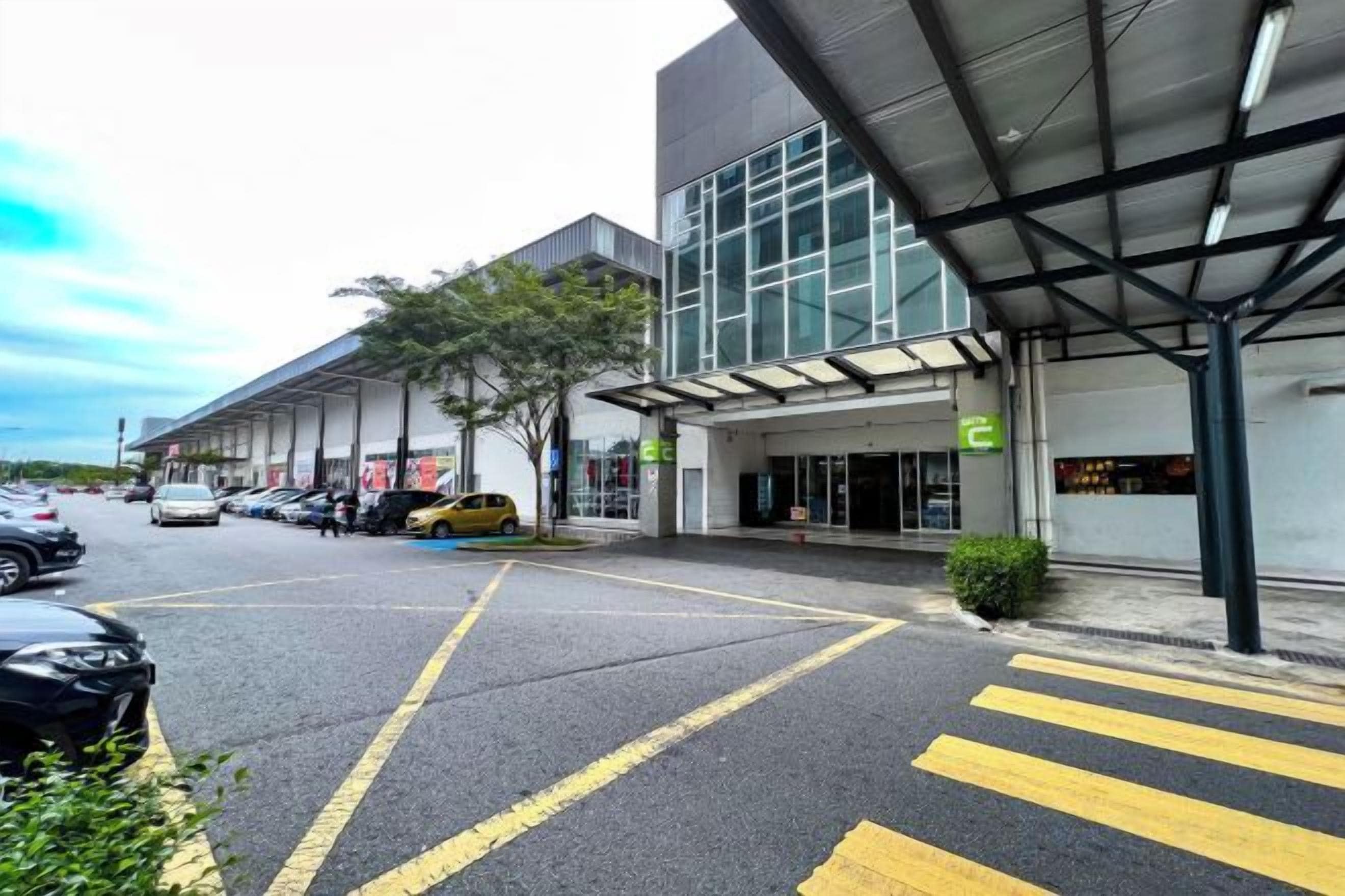 A parking lot with marked lanes, a building entrance with a covered area, and a sign indicating a hotel.
