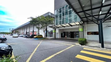 A parking lot with marked lanes, a building entrance with a covered area, and a sign indicating a hotel.