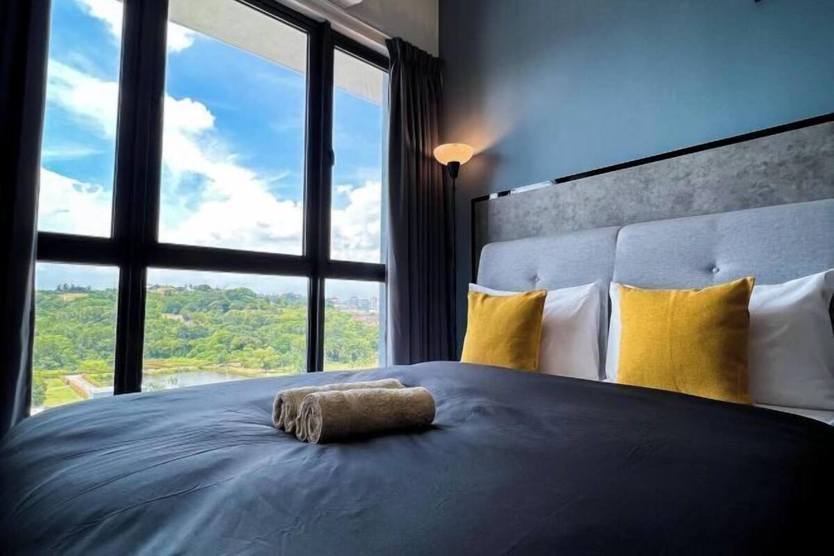 A bed with a view of a landscape through large windows.
