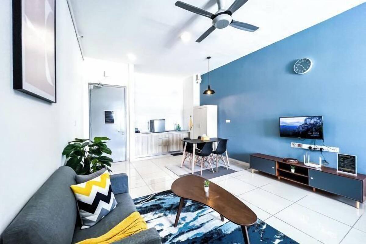 A modern living room with a sofa, a coffee table, a TV, and a dining area with chairs and a table.