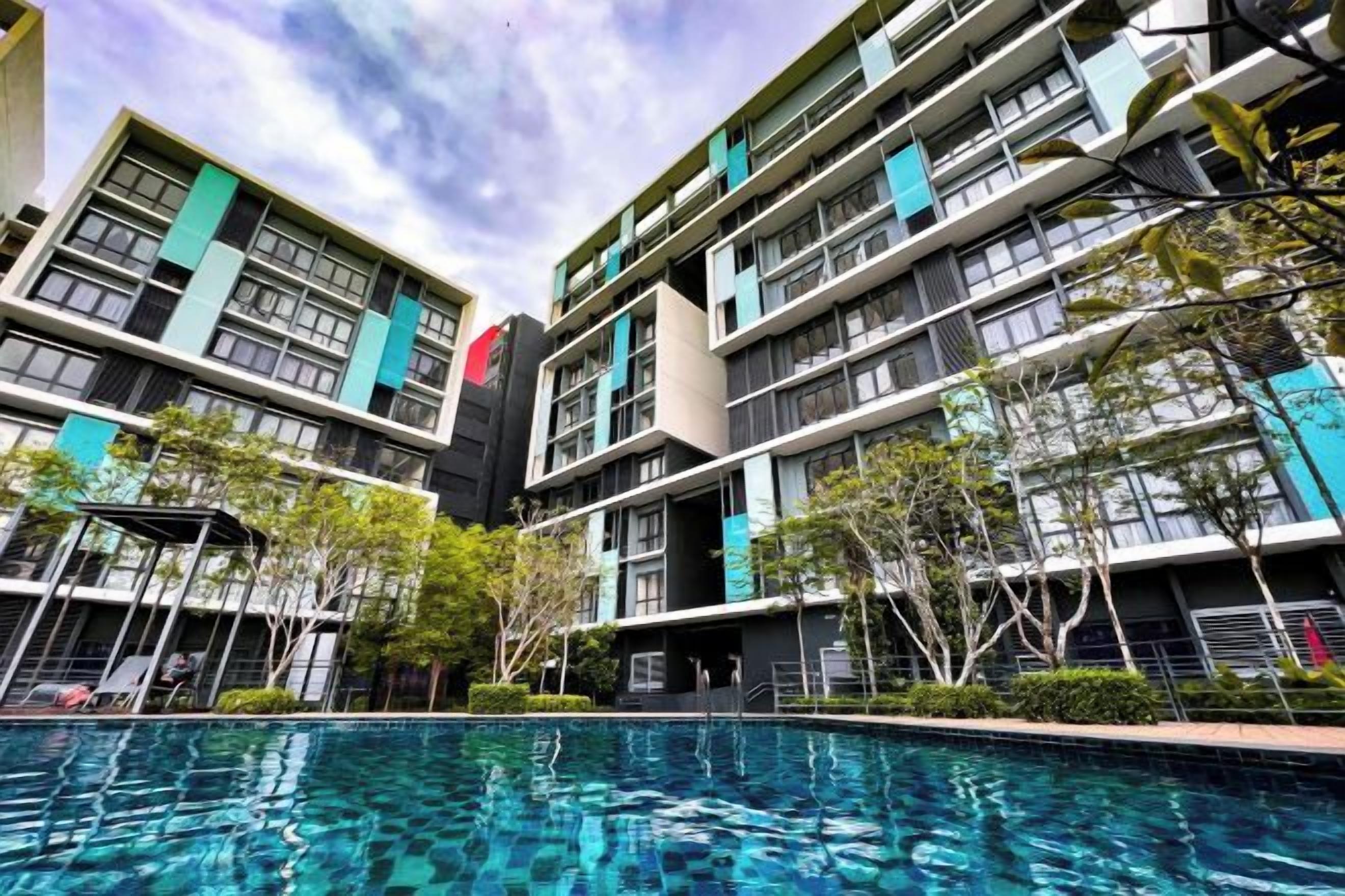 A multi-story hotel with a swimming pool, outdoor seating, and a modern architectural design.
