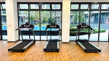 A gym with three treadmills, large windows, and a wooden floor.