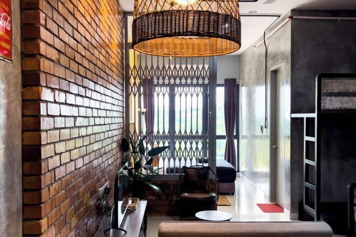 A modern interior with a brick wall, a woven light fixture, and a seating area with a sofa and chairs.